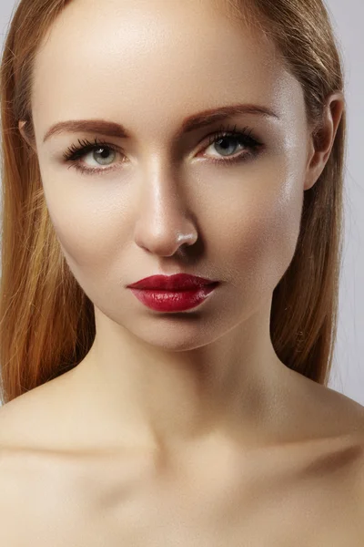 Hermosa modelo con maquillaje de moda. Retrato de cerca mujer sexy con glamour maquillaje brillo labial y maquillaje delineador de ojos negro. Tiro de celebrar el rostro, piel limpia, labios con lápiz labial rojo, cejas — Foto de Stock