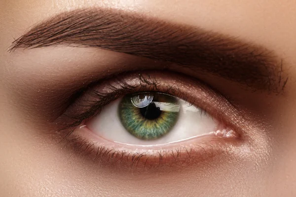 Hermoso macroplano de ojo femenino verde con maquillaje natural. Forma perfecta de cejas, sombras marrones y pestañas largas. Cosméticos y maquillaje. Primer plano macro disparo de moda ojos ahumados visage . — Foto de Stock