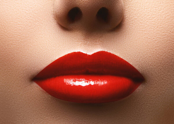 Крупный план красивых губ с красным глянцевым макияжем. Идеальная яркая помада. Пластическая хирургия или концепция макияжа. Чистая кожа и пухлые губы