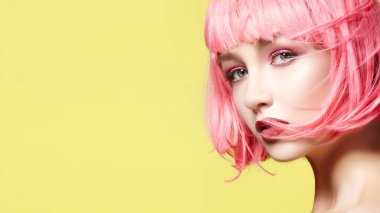 Pembe Peruklu Genç Model. Moda makyajlı güzel bir model. Parlak Bahar Bakışı. Kopya Boşluğu ile Sarı Arkaplanda Seksi Saç Rengi, Orta Saç Tarzı