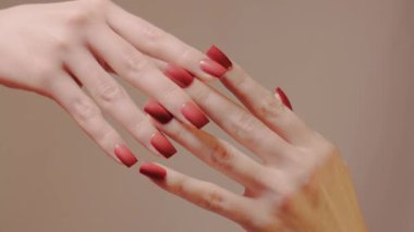 Kırmızı manikürlü elleri yakın çekim, birbirine sürtünme ve ayrılma. Moda tırnak şekli ve jöle parlatıcısı, cilt bakımı. Ayrılığın sembolü, ilişkilerin. Güzellik, manikürlü tırnaklar.