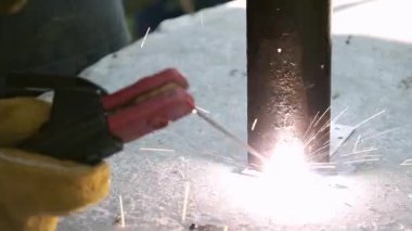 Çelik yüzeyde metal kaynak borusu, yoğun ışık ve ısı. Endüstriyel iş, hassasiyet, profesyonel işçilikte güç. Elektrot ve eldivenli işçilere yakın çekim. Metalurji veya araç için.