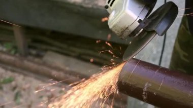 Metal boruyu öğütücüyle kesen işçiler endüstriyel çalışma sürecinde parlak kıvılcımlar üretiyorlar. Dayanıklılık, hassasiyet ve ustalık. Sıkı çalışma ve çalışma. Bir inşaat ya da alet şirketi için..