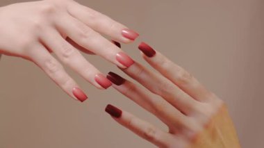 Eller, kırmızı manikür ve pürüzsüz cilalama katmanlarını vurgulamak için parmakları yavaşça birbirine geçirir. Lüks salon içeriği için samimiyet, bakım ve zanaatkar tırnak işçiliği. Manikür sanatının güzel bir resmi..