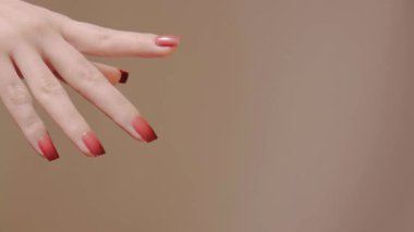 Kapat Kırmızı manikürlü bir el aşağı ve parmaklarını esnetir, tırnak hatlarını gösterir, cilalama kalitesi ve el çevikliği özel dersler ve güzellik ayrıntıları için uygundur.