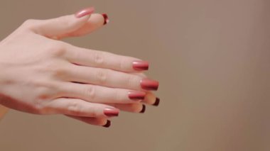 Avuçlar nazikçe birbirine sürterek oje tabakalarını ve yumuşak deriyi gösterir. Kırmızı manikür detaylarıyla spa ve kişisel bakım için ideal jestleri birleştiriyor. Manikür sanatının moda güzelliği..