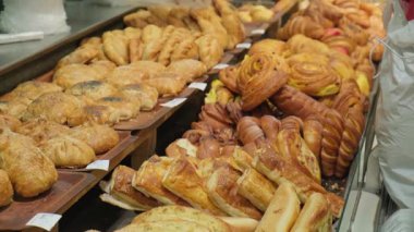 Konforlu bir fırın veya kafeterya vitrininde sergilenen çeşitli yeni pişmiş hamur işleri, kruvasanlar, kruvasanlar, kekler ve tatlı ekmekler, ayrıca bir market dekorasyonu, zanaatkar ekmek ve davet edici kahvaltı, brunch ve tatlı