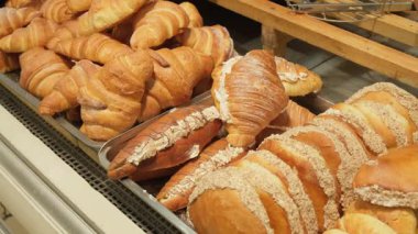 Konforlu bir fırın veya kafeterya vitrininde sergilenen çeşitli yeni pişmiş hamur işleri, kruvasanlar, kruvasanlar, kekler ve tatlı ekmekler, ayrıca bir market dekorasyonu, zanaatkar ekmek ve davet edici kahvaltı, brunch ve tatlı