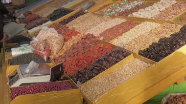 Canlı Orta Asya pazar tezgahı fındık, kurutulmuş meyve, doğal tatlılar ve çeşitli organik ürünlerin karışımı, tazelik, kalite ve çeşitliliği vurgulamak üzere tasarlanmış büyük bir durumda sergilenmektedir..