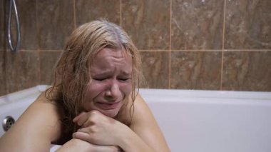 Depresyon konsepti, zihinsel mücadele, yalnızlık veya kötü muamele sorunu. Sarışın kadın küvette oturup ağlıyor, göz yaşları akıyor, göz makyajı yapıyor, kederli bakışlar, banyo, ızdırap, duygusal acı.