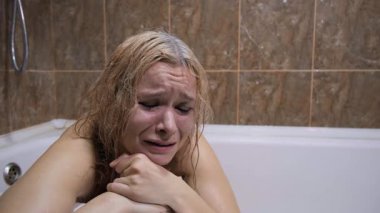 Duygusal sıkıntı, ruhsal bozukluk, tecrit ya da istismar durumu. Sarışın kadın küvette ağlıyor, gözyaşları yüzünden akıyor, makyaj lekesi, acı dolu ifade, banyo, umutsuzluk, depresyon durumu.