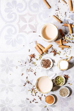 Masala çayı, tarçın çubukları, yeşil kakule tohumları ve gri doku arka planında anason ile servis edilir. Üst Manzara. Düz yat. Boşluğu kopyala