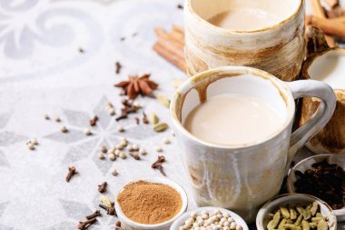 Masala çayı, tarçın çubukları, yeşil kakule tohumları ve gri doku arka planında anason ile servis edilir.