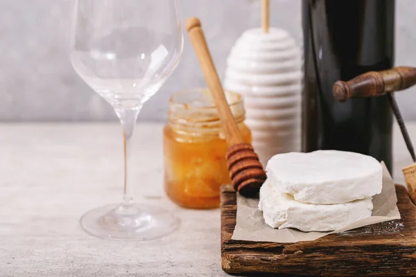 白い食感を背景に 蜂蜜と赤ワインのボトルを添えたヤギチーズ スペースのコピー — ストック写真