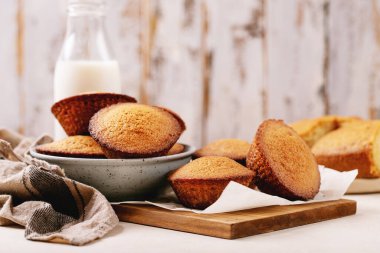 Beyaz dokuya sahip şişedeki sütle servis edilen ev yapımı kekler.