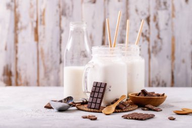 Beyaz desenli arkaplanda çikolata ile servis edilen vanilyalı milkshake.