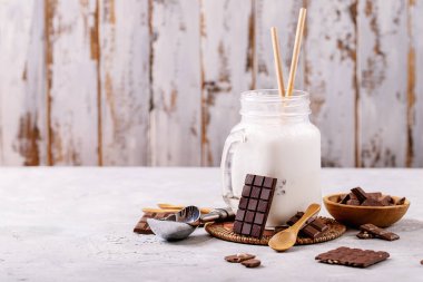 Beyaz desenli arkaplanda çikolata ile servis edilen vanilyalı milkshake.