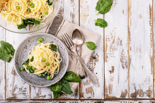 Italian food: Fresh home made tagliatelle vegetarian egg pasta Carbonara served with ricotta cheese and spinach over white wooden background. Top view, flat lay. Copy space