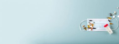 Tıbbi ilaçlar ve tıbbi maskeli kapsüller mavi dokuda. COVID-19. Üst Manzara. Uzayı kopyala Pankart