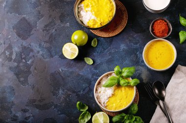 Koyu arkaplanda fesleğen ve limonla servis edilen sarı körili seramik kase. Üst manzara, düz yatış. Boşluğu kopyala