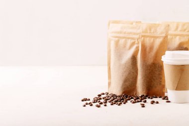 Kağıt bardakları, kahve çekirdeklerini ve beyaz desenli logo için boş alanları olan kahve paketlerini çıkarın. Boşluğu kopyala