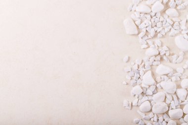 Beyaz desenli arka plan üzerinde beyaz süslemeli taşlar ve çakıl taşları. Doğanın yaratıcı düzeni. Tasarım için boşluk
