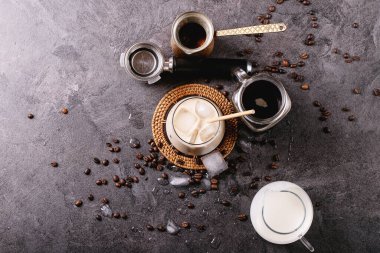 Krema ve kahve çekirdekleri ile servis edilen buzlu kahve koyu desenli arka plan. Üst manzara, düz yatış. Boşluğu kopyala