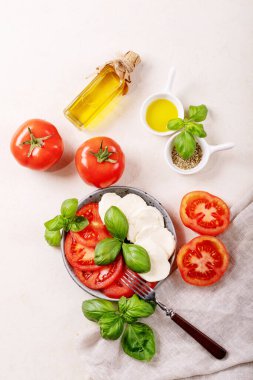 Ev yapımı sağlıklı yemek konsepti: kiraz domatesleri, mozarella topları, baharatlar, zeytinyağı ve taze fesleğen. Beyaz desenli Mozzarella salatası. Uzayı kopyala Üst manzara, düz uzanma