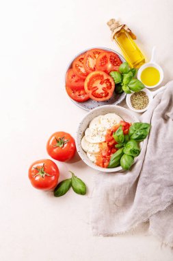 Ev yapımı sağlıklı yemek konsepti: kiraz domatesleri, mozarella topları, baharatlar, zeytinyağı ve taze fesleğen. Beyaz desenli Mozzarella salatası. Uzayı kopyala Üst manzara, düz uzanma