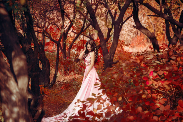 Lady in a luxury lush pink pastel dress near the tree,fantastic shot,fairytale princess is walking in the autumn forest,fashionable toning,creative computer colors
