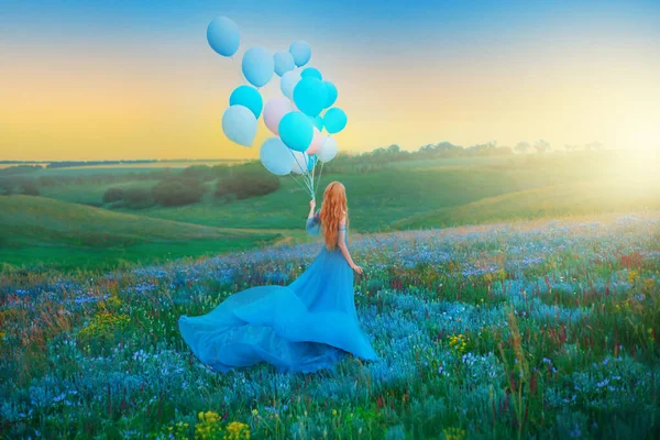 Szczęśliwa kobieta. Fantasy girl księżniczka trzyma w ręku balon powietrza. długi niebieski tiul sukienka trzepotanie mucha na wietrze. Zachód słońca niebo mgła, kolorowe kwiaty zielona łąka. blond rude włosy, widok z tyłu — Zdjęcie stockowe