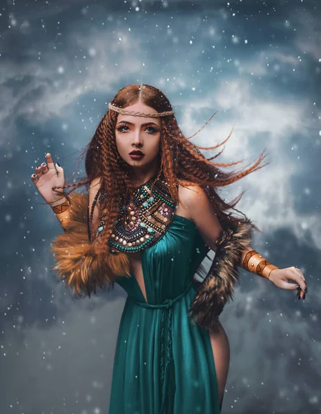 Kızıl saçlı fantezi kadın bulutlarda duruyor. Moda modeli stüdyoda poz veriyor dramatik kış gökyüzü, duman. Elf prensesi kız. Rüzgarda uçuşan uzun kızıl saçlar kar yağıyor. Mavi elbise etnik makyaj. — Stok fotoğraf