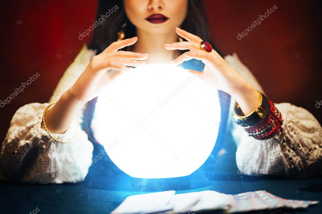 Fantasy beautiful retro womens hands close-up, look feel energy of crystal ball in dark gothic room. Photo of old art vintage astrology. Fortune teller woman reading future on magical tarot cards