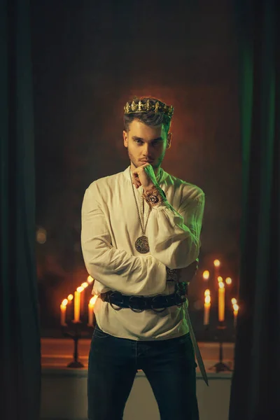 Portrait of handsome attractive man in image of medieval king. Vintage clothing historic white shirt retro clothing gold crown on head. Dark gothic room, studio. Fashion model. Adult sexy guy knight — Stock Photo, Image