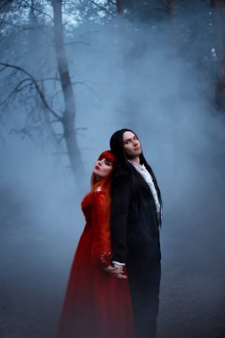 Eski korku filmi tarzı buğday eklendi. Siste duran gotik bir çift. Siyah paltolu vampir prens kadınları baştan çıkarıyor. kırmızı ortaçağ elbisesi. Uzun saçlı kız prenses. Gizemli karanlık ağaç doğası..