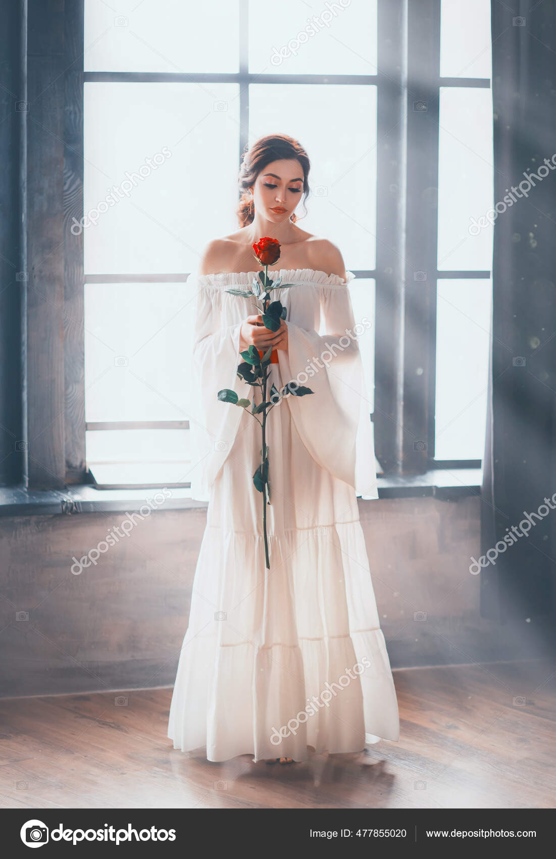 Fantasy vintage beauty woman sexy bare shoulders. white long medieval dress wide sleeves renaissance style. Lady holds red rose in hands stands on window with magical bright sun ray sunlight. —