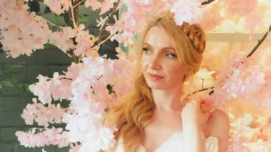 Portre mutlu romantik fantezi sarışın kadın prenses beyaz klasik elbise içinde. Cazibeli doğal yumuşak makyaj nazik gülen yüz. Sarı saçlar. Çiçek açan ağacın bahar doğası dalı, pembe çiçekler..