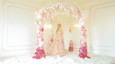 Portre fantezi sarışın kadın dans ediyor, gülümseyen neşeli yüz. Pembe çiçekli elbisesini sallayan bahar perisi prenses kız. Beyaz oda şık gelin sarı saç, düğün kemeri, resmi tören