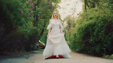 Joyful beautiful happy woman running on road, long white vintage boho style dress fluttering in wind motion. fantasy girl princess bride goes to meet groom love. Summer nature green trees wedding day