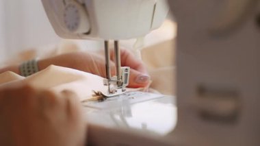 senior woman tailor sewing clothes using sewing machine, process of creating dress. Close-up hands seamstresss fabric stitching. female fashion designer work. elderly lady hobby home workshop space.