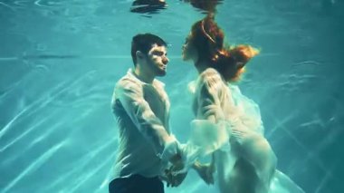 Fantezi romantik çift aşık olur erkek kral ve kadın su altında kucaklaşır. Islak beyaz elbise. Kızıl saçlı seksi kız Yunan tanrıçası nehir perisi deniz kızı yüzücüleri boğulan adamı baştan çıkarır. Yaratıcı çekim