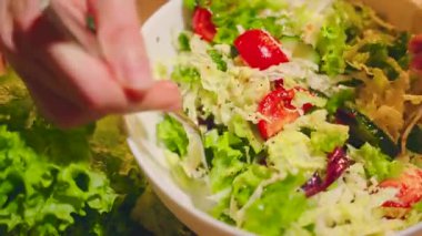 Sağlıklı beslenme konsepti. Mutfak masasında akşam yemeği için yeşil sebze salatası hazırlayan yakın çekim el silueti. Kadın taze sebze salatasıyla çatalı tabakta karıştırıyor. gövde parçası.