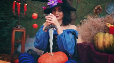 Portre fantezisi mutlu kadın cadı hançer bıçak tutuyor Cadılar bayramı için balkabağı oymaya hazır. Neşeli kız yaratıcı kostüm siyah mor külah şapka. Gülen yüz sanat makyajı. Sonbahar doğası