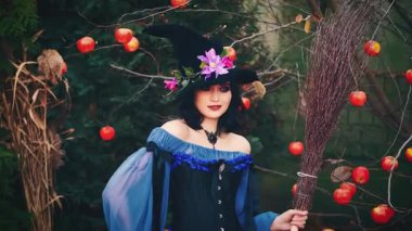 Cadılar Bayramı portresi mutlu fantezi kadın elinde süpürgeyle dans ediyor. Klasik mor kostüm ortaçağ elbisesi, sanat uzun koni şapkası. Sihirbaz bayan model seksi kız pozu. sonbahar arkaplanı.