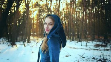 Portre yakın fantezi mutlu orta çağ kadını kapüşonlu. Şirin, romantik, gülen surat. Yetişkin prenses kız doğanın tadını çıkarıyor. Eski moda mavi elbise. Kış ormanı, kar, günbatımı sihirli ışık. 