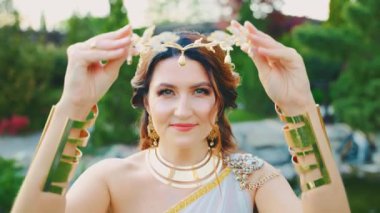 Fantezi kadın tanrıça, altın tacı elinde tutuyor antik Yunan tarzı baş çelengi takıyor kraliyet tacını. Manken kız kraliçesi. beyaz ipek lüks elbise altın metal elmas mücevher