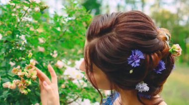 Kadın elinin portresi beyaz çiçeklere hafifçe dokunuyor yeşil yapraklar ağaçlara. Güzel kız gülümseyen yüz seksi makyaj. Kadınlar doğayı sever. Mavi çiçek arkaplan görünümlü zarif akşam saç stili toplandı