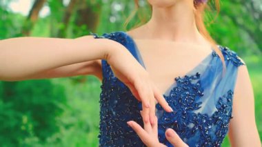 Genç esmer bir kadın elleriyle tenine dokunuyor. Moda mankeni, seksi bir kız. Boynunu okşuyor. Akşam saç stili romantik mavi elbise. Yaz doğası yeşil ağaçlar park