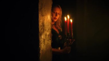 Ortaçağ fantezi kadını karanlık odada elinde şamdanla elinde mumlarla sihirli, sıcak bir ışık yakıyor. Başında kapüşon olan eski tarz yeşil bir pelerin. Seksi kız vampir. Gece Siyah Kale