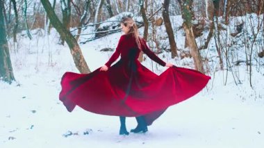 Fantezi mutlu kadın dönüyor, dans ediyor, etek tutuyor uzun elbiseler ellerinde, kırmızı kumaş rüzgarda dalgalanıyor. Prenses kız kış doğasının tadını çıkarıyor. Taze, soğuk, beyaz, kar ağacı, donmuş prenses. Bayan sanat 4k